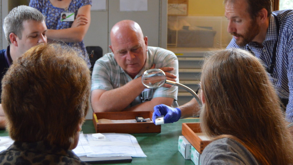 Volunteers look at a current Treasure find held in the hand of Ian Richardson, Treasure Registrar