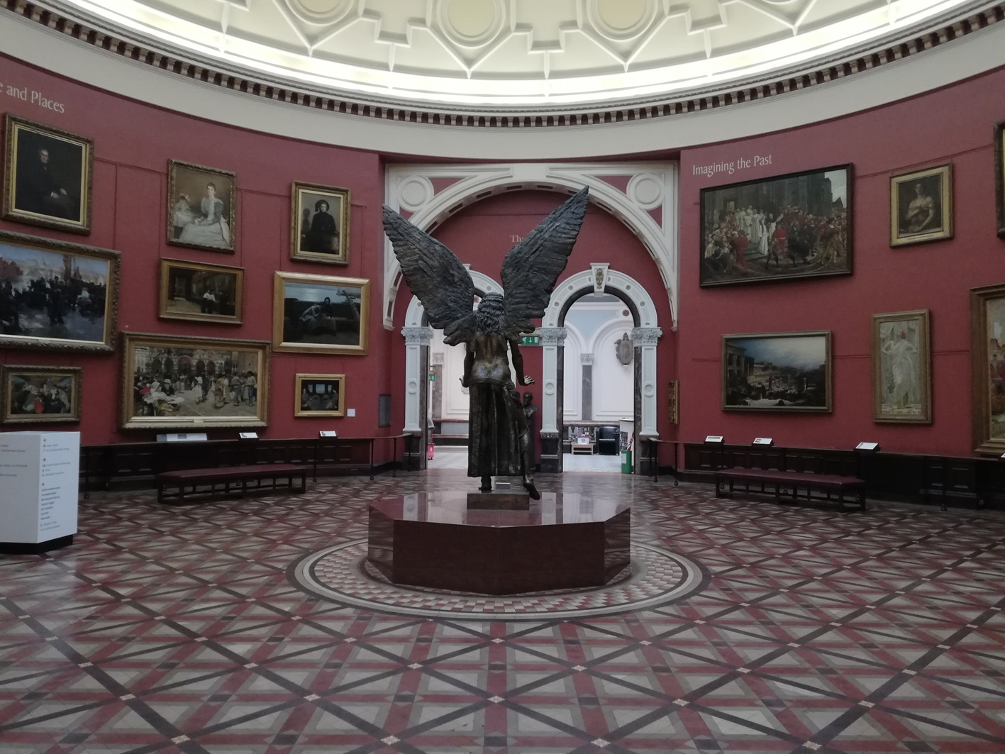 paintings hanging on the wall of the round room at Birmingham museum and art gallery and Sir Jacob Epstein's Lucifer bronze statue from the back