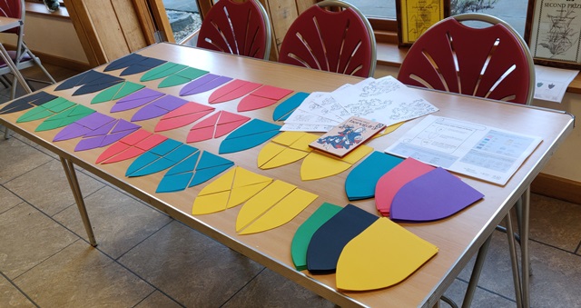 Image showing a table with coloured paper shields for a craft activity.