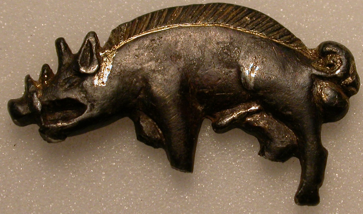 Image of a silver badge in the shape of a wild boar.